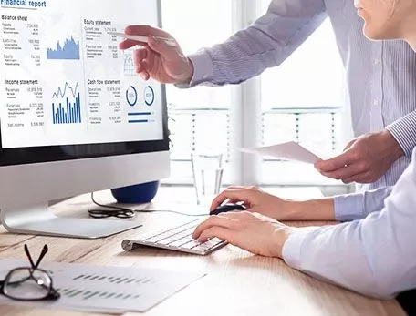 Two people reviewing a financial report on a computer screen.