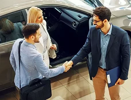 Two men shaking hands while a woman watches.